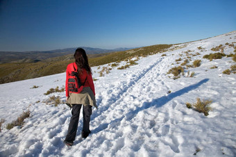 女人背包雪路径