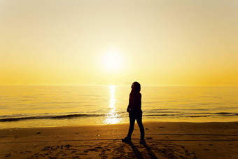 年轻的女人站海滩日落