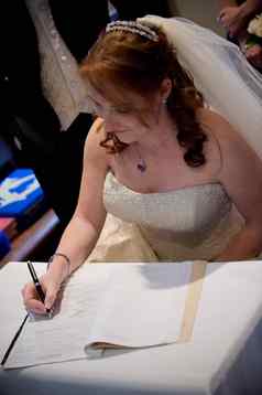 美丽的红色的头发新娘签署婚礼注册黑色的笔