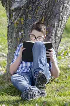 年轻的男孩阅读书森林浅深度忠诚