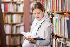 年轻的怀孕了女人阅读书图书馆