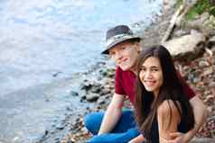 美丽的年轻的跨种族夫妇坐着湖肖
