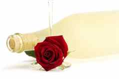 湿红色的玫瑰空香槟玻璃前面普罗瓶