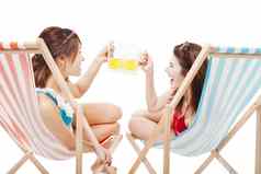 阳光女孩持有啤酒干杯海滩椅子