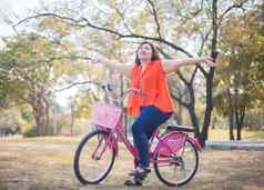 快乐高脂肪的女人摆姿势自行车