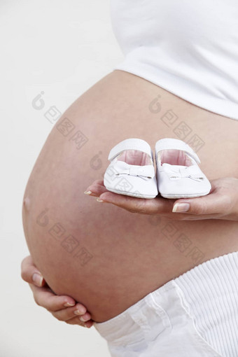 关闭怀孕了女人持有婴儿鞋子