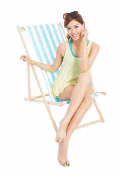 漂亮的阳光女孩微笑坐着海滩椅子