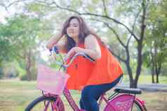 快乐高脂肪的女人摆姿势自行车
