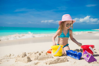 可爱的女孩玩海滩白色沙子