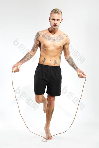 有吸引力的年轻的男孩跳绳子纹身体育裤子