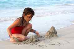 美丽的女孩建筑沙子城堡海滩