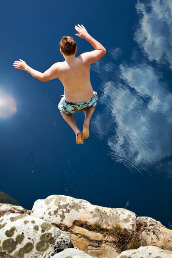 男孩跳悬崖蓝色的水