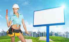 女人工具带持有扳手软管绿色山路建筑广告牌背景