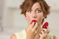 漂亮的睁大眼睛红色的头发的女人咬草莓