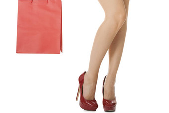 女人腿红色的高高跟鞋携带红色的袋