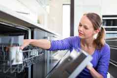做家务年轻的女人把菜洗碗机