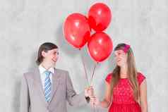 复合图像微笑极客夫妇持有红色的气球