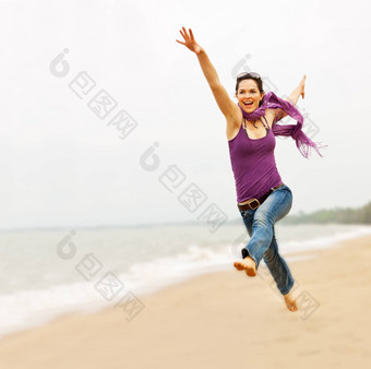 美丽的年轻的女人采取伟大的飞跃海滩
