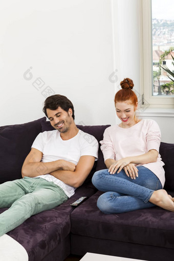 快乐年轻的甜蜜的夫妇坐着沙发上