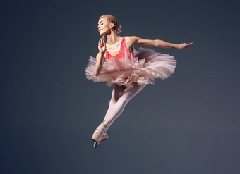 美丽的女芭蕾舞舞者灰色背景芭蕾舞女演员穿粉红色的图图尖端鞋子