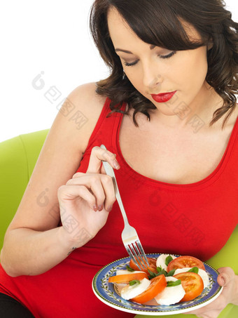 年轻的女人吃马苏里拉奶酪奶酪番茄沙拉