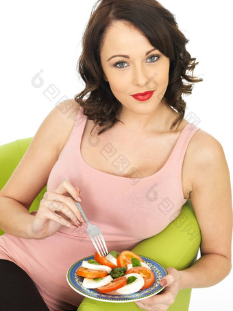 年轻的女人吃马苏里拉奶酪奶酪番茄沙拉