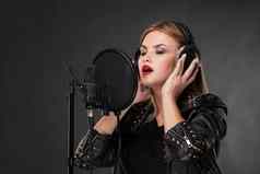 肖像美丽的女人唱歌麦克风耳机工作室黑色的背景