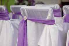 美丽的白色婚礼椅子装饰紫色的弓