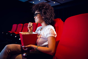 年轻的女人看电影吃流行玉米