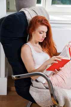 年轻的女人坐着椅子阅读书