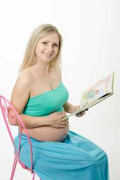 怀孕了年轻的女人坐着椅子阅读书