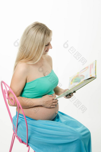 怀孕了年轻的女人阅读书坐着椅子