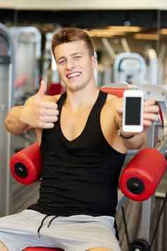 微笑年轻的男人。智能手机健身房