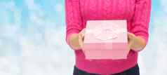 关闭女人粉红色的毛衣持有礼物盒子
