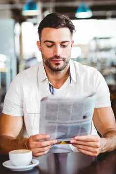 年轻的男人。杯咖啡阅读报纸