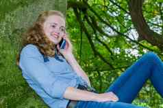 荷兰十几岁的女孩打电话移动绿色树