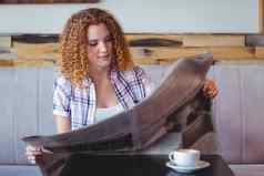 漂亮的卷曲的头发女孩杯咖啡阅读报纸