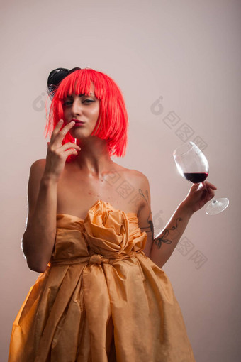 有吸引力的可爱的女人红色的假发摆姿势玻璃酒