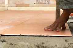 男人。建设工人瓷砖首页瓷砖地板上胶粘剂