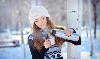 美丽的浅黑肤色的女人倒咖啡热水瓶走冬天