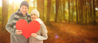 复合图像快乐成熟的夫妇冬天衣服持有红色的心