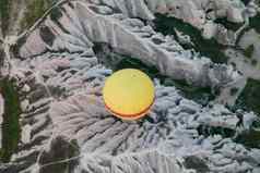 空中拍摄黄色的热空气气球前洞穴火山