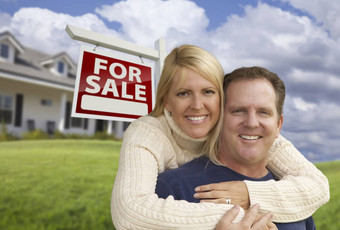 快乐夫妇拥抱前面真正的房地产标志房子