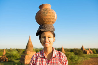 年轻的亚洲传统的女农民携带粘土能头