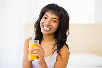 休闲微笑女人持有玻璃橙色汁