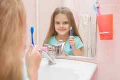 一年女孩开放口对待牙齿反射镜子浴室