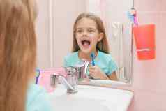 一年女孩开放口对待牙齿反射镜子浴室