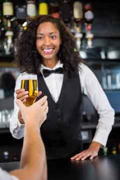美丽的酒吧女招待服务啤酒男人。