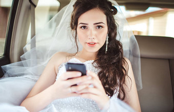 美丽的新娘坐着车直移动电话发型明亮的化妆