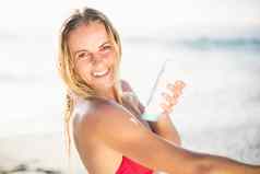 肖像快乐女人应用防晒霜乳液海滩